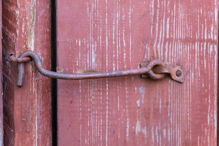 Vintage iron wire door hook on the closed old painted wooden door outdoorsの写真素材