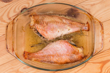Two baked redfishes without heads, also known as ocean perch in the old glass baking dish on a...
