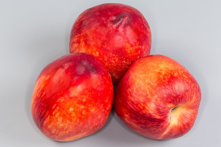 Three fresh ripe nectarines on a gray background close-upの写真素材
