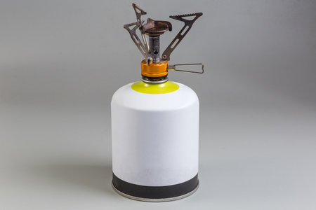 Portable gas burner installed on a disposable metal gas cartridge for camping stoves on a gray backgroundの写真素材