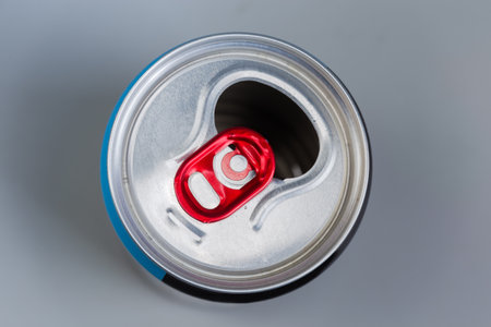 Used open empty aluminum beverage can with silvery top and red pull tab on a gray background, top viewの写真素材