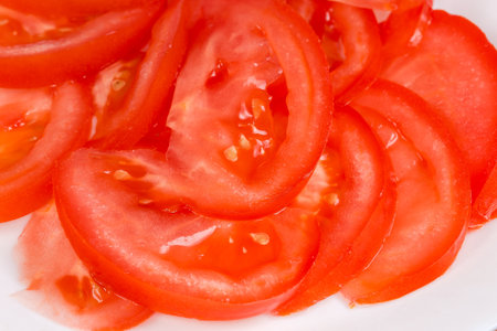 Slices of the fresh red tomato on dish, close-up in selective focusの写真素材