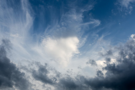 Edge of the storm cloud against the blue sky with cirrus clouds