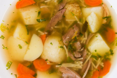 Freshly prepared hot homemade chicken soup with thin short vermicelli, top view of fragment close-upの写真素材