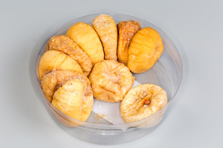 Dried whole figs in the small round plastic partially filled packaging on a gray backgroundの写真素材