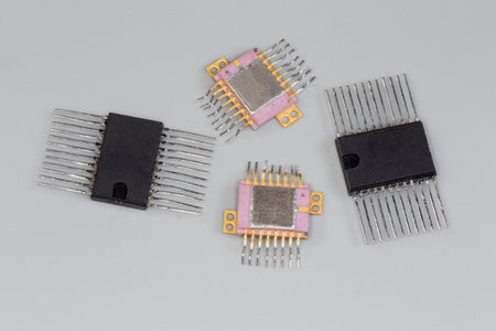 Integrated circuits in the plastic and metal-ceramic rectangular packages with dual-side planar pins for surface mount on printed circuit board close-up on a gray surfaceの写真素材