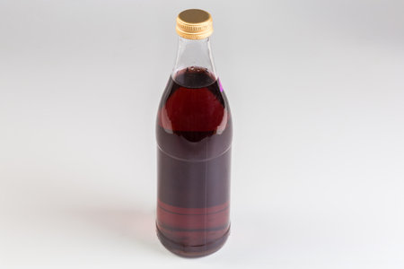 Red cold non-alcoholic carbonated fruits drink in the closed glass bottle on a gray backgroundの写真素材