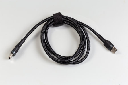 Coiled black braided slicing cable USB with plugs USB Type-C at the both edges on a gray backgroundの写真素材