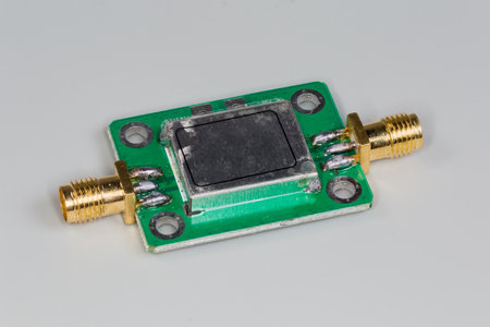 Miniature high-frequency electronic unit with two yellow coaxial connectors on the opposite edges on...