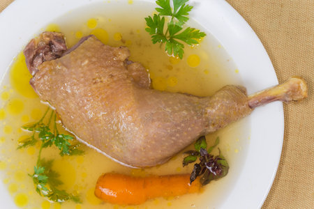 Boiled leg quarter of domestic chicken reared by free range method outdoors in a bouillon obtained by boiling this meat on dish, top view close-upの写真素材