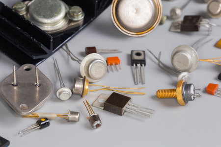 Old bipolar and field-effect transistors for various purposes in different metal, ceramic and plastic packages on a gray surface, fragment close-up in selective focusの写真素材