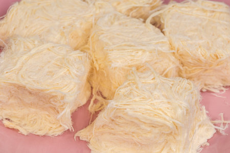 Traditional Turkish sweets pishmanie in form of the pieces of pressed flosses made of flour with pulled sugar on a pink dish, close-up in selective focusの写真素材