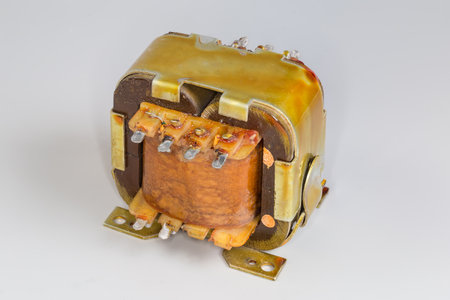 Old compact mains shell type transformer for various household or industrial device power supply on a gray surfaceの写真素材