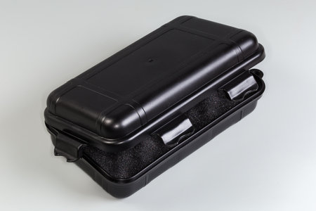Small partly open plastic black portable toolbox per one compartment with soft foam inserts inside for storage and carrying of tools and other purposes on a gray backgroundの写真素材