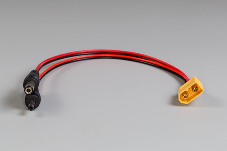 Power cable-adapter with two different coaxial plugs on one cable edge and flat connector with two pins on the other edge on a gray backgroundの写真素材