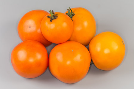 Small heap of whole ripe organic round yellow tomatoes on a gray backgroundの写真素材