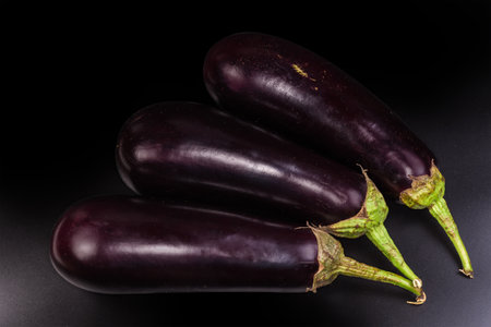 Freshly harvested ripe whole purple eggplants on a black background, top viewの写真素材