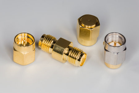 Various yellow and silvery coaxial high-frequency threaded adapters and plugs on a gray surface, close-upの写真素材
