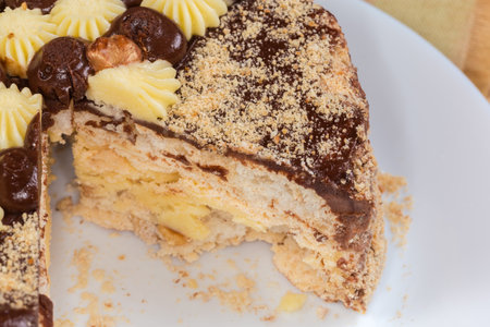 Partly cut round layered sponge cake decorated with milk and white chocolate atop, fragment close-up in selective focusの写真素材