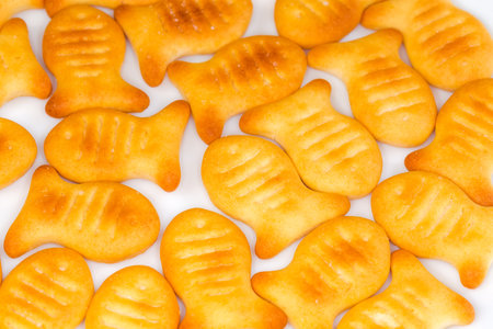 Salty crackers in the form of small fishes laid in one layer on a white dish, close-up in selective focusの写真素材