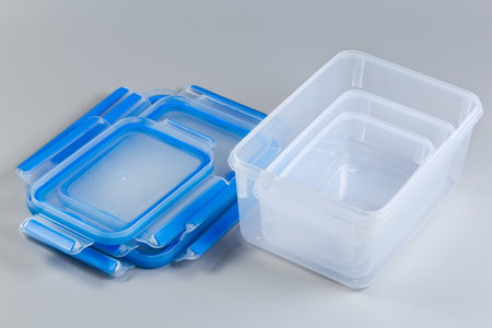 Set of empty reusable transparent plastic food storage containers different sizes with removed stacked blue lids on a gray backgroundの写真素材