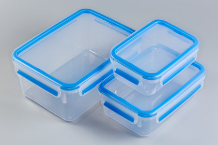 Set of empty reusable transparent plastic food storage containers different sizes with closed blue...