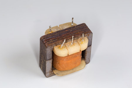 Old small-sized mains shell type transformer without the casing designed for various household device power supply on a gray surfaceの写真素材