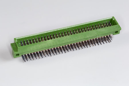 Three row male electrical connector in green plastic housing with right angle terminals which may be soldered to the printed circuit board, view on a gray surface in selective focusの写真素材