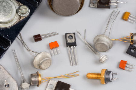 Old bipolar and field-effect transistors for various purposes in different metal, ceramic and plastic packages on a gray surface, fragment close-up in selective focusの写真素材