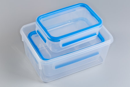Set of empty reusable transparent plastic food storage containers different sizes with blue lids on a gray backgroundの写真素材