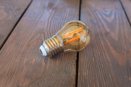 LED Edison lamp of attractive design in retro style in glass bulb with led filaments and male screw base on the old wooden rustic table, selective focusの写真素材