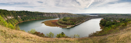 Bends of the Zbruch river leaking in canyon-like valley with steep rock banks not far from the mouth, panoramic view at autumn overcast dayの写真素材