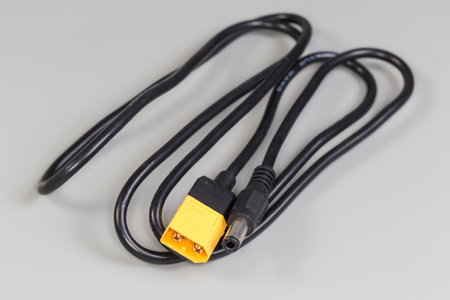 Power cable-adapter with coaxial plug on one cable edge and flat connector with two pins on the...