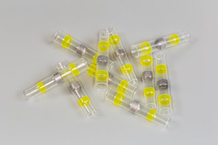 Heap of yellow heat shrink tubes with solder ring inside in center, so called solder sleeves for...