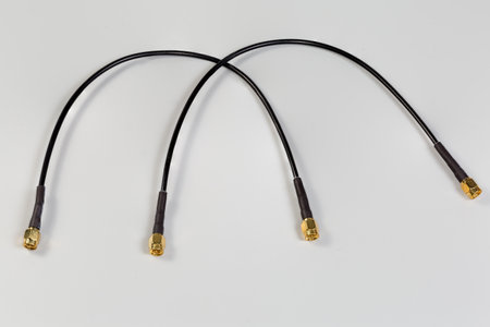 Two black high-frequency cable adapters with yellow male coaxial threaded male connectors on the edges on a gray surfaceの写真素材