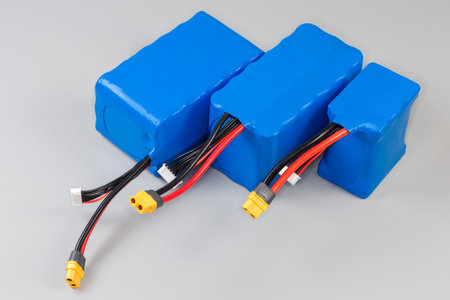 Different rechargeable battery packs with power and control wires in blue plastic covering for power supply of UAV and other mobile devices on a gray backgroundの写真素材