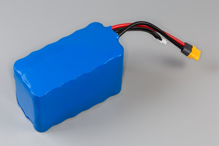 Rechargeable battery pack with power and control wires in blue plastic covering for power supply for UAV and other mobile devices on a gray backgroundの写真素材