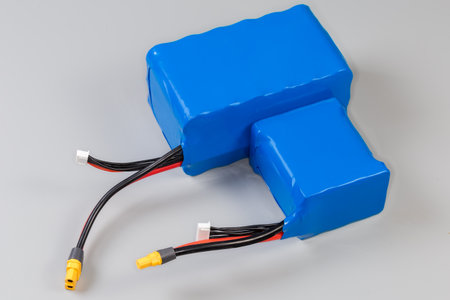 Two different rechargeable battery packs with power and control wires in blue plastic covering for power supply of UAV and other mobile devices on a gray backgroundの写真素材