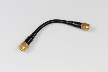 Short black high-frequency cable adapter with yellow coaxial threaded connectors on the edges on a...