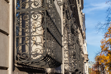 Decorative black metal security window bars installed on the ground-floor windows close-up in selective focus, view along the wall in sunny weatherの写真素材