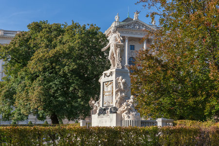 Mozart monument created in the 19th century, now located in the City garden, Vienna, Austria. View on a background of the New Castle of Hofburg and trees in autumn sunny dayの写真素材
