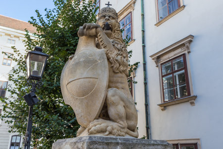 Sculpture of lion in crown and with shield in front of the Swiss Gate in Castle Hofburg, Vienna, Austria, view in a shade in sunny dayの写真素材