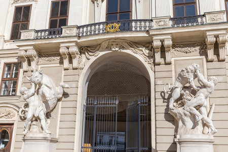 Two sculptures of Hercules in south-western facade of Imperial Chancellery of the St. Michael's Wing of the Hofburg in sunny day, Vienna, Austriaの写真素材