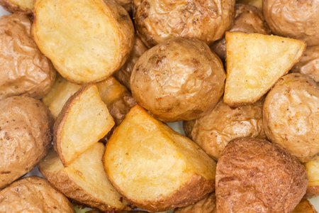 Pieces of potato baked in their skins in a peasant style, top view close-up in selective focusの写真素材