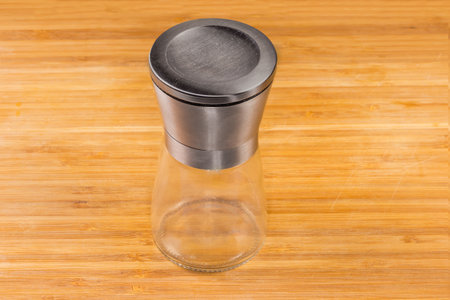 Handmade stainless steel spice mill with empty glass container for grinded spices on a wooden surfaceの写真素材
