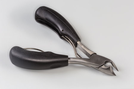 Professional stainless steel pedicure nail clipper with curved blades for grooming of thick and ingrown nails on a gray backgroundの写真素材