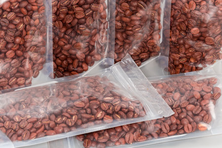Roasted coffee beans in the plastic food-grade transparent reclosable zipper bags, fragment close-up in selective focusの写真素材