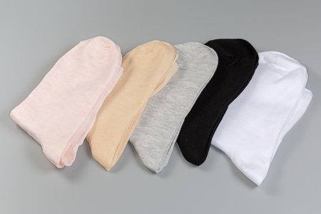 Several pairs of the folded thin everyday women's socks of different colors on a gray surfaceの写真素材