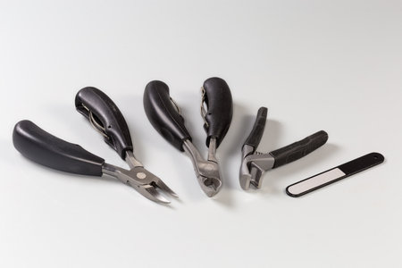 Set of different professional stainless steel nail clippers of different design and nail file for grooming of thick and ingrown nails on a gray surface, close-up selective focusの写真素材