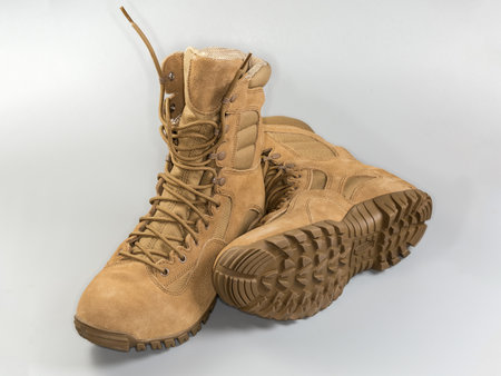 Pair of the waterproofed insulated beige leather combat boots on shoelaces on a gray backgroundの写真素材
